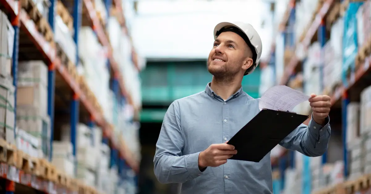 Male professional inspecting warehouse shelves with a clipboard, symbolizing efficient inventory tracking and management