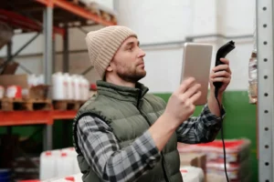 Warehouse worker scanning inventory with a handheld device, showcasing how ERP improves inventory tracking and accuracy.