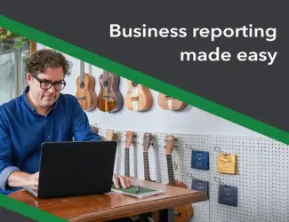 Man working on a laptop in a small business setting, with the text 'Business reporting made easy,' representing QuickBooks' strengths in simplifying reporting for small to medium businesses